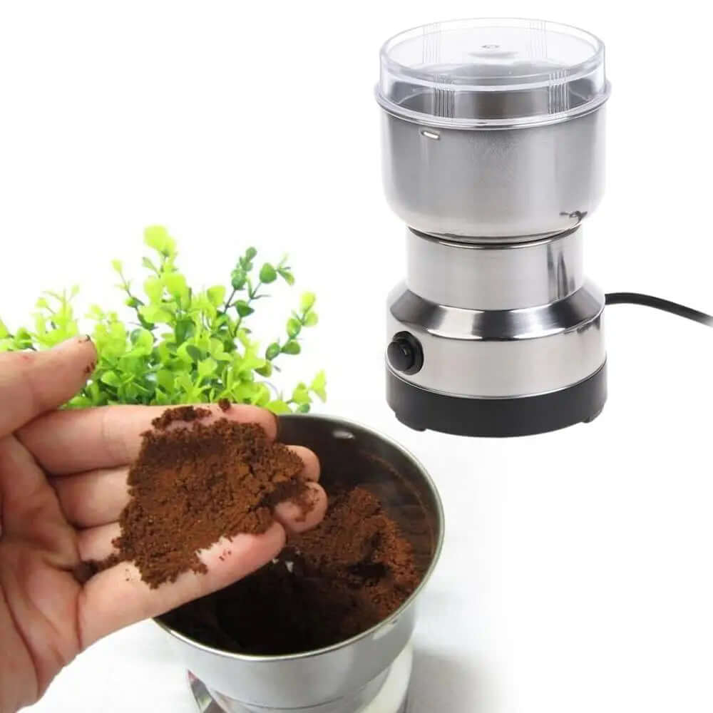 Stainless steel electric coffee grinder with ground coffee and plant in background