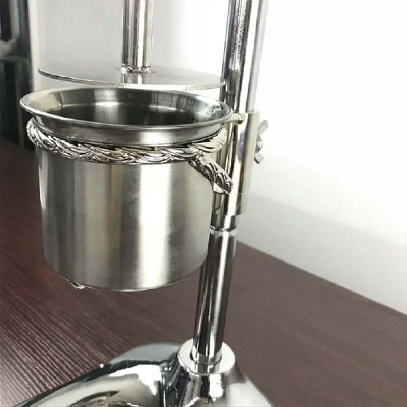 Stainless steel kitchen tool on stand with polished metal cup on wooden surface