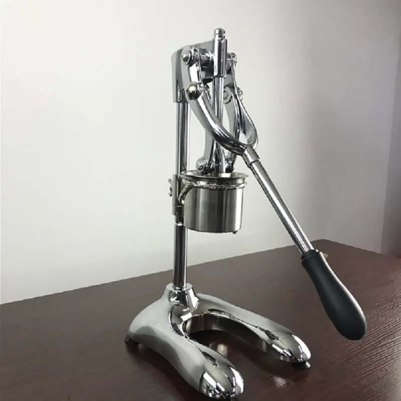 Stainless steel manual citrus juicer with black handle on wooden kitchen counter