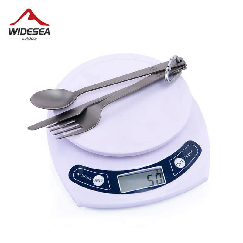 Titanium camping cutlery set with spoon, fork, and knife on digital kitchen scale
