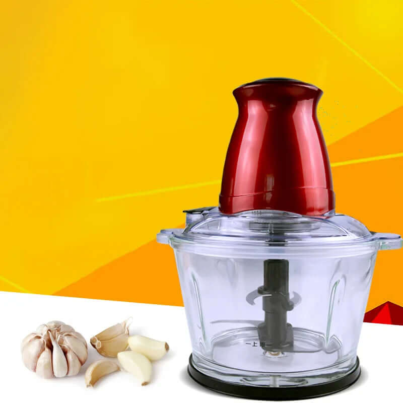 Electric food chopper with red lid and glass bowl beside garlic on yellow background