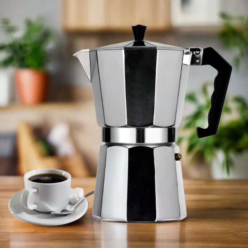 Stovetop moka pot coffee maker and full cup of coffee on kitchen table
