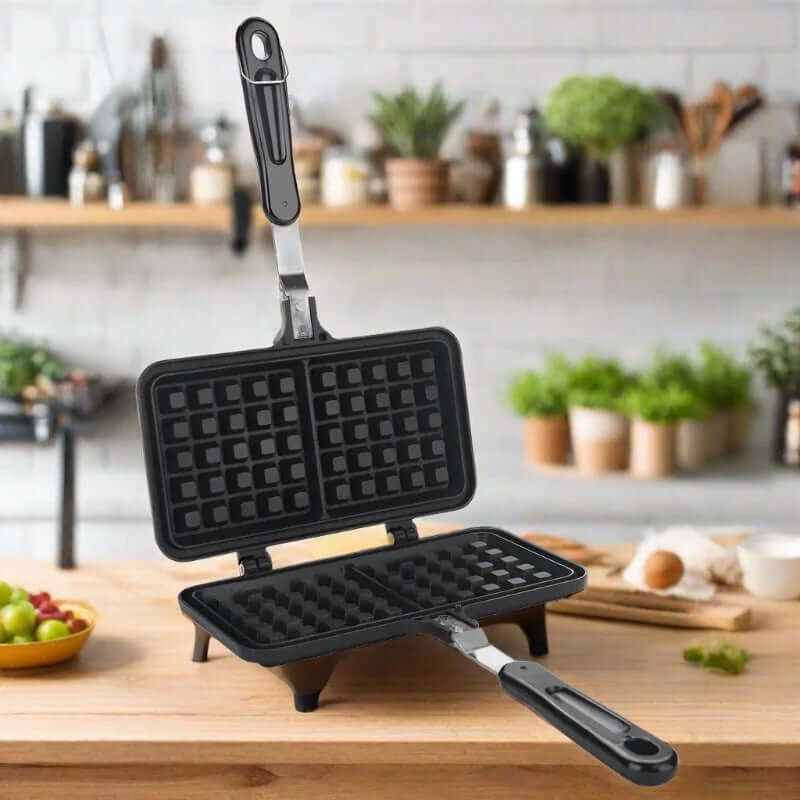 Open non-stick waffle maker with black handles on a kitchen countertop