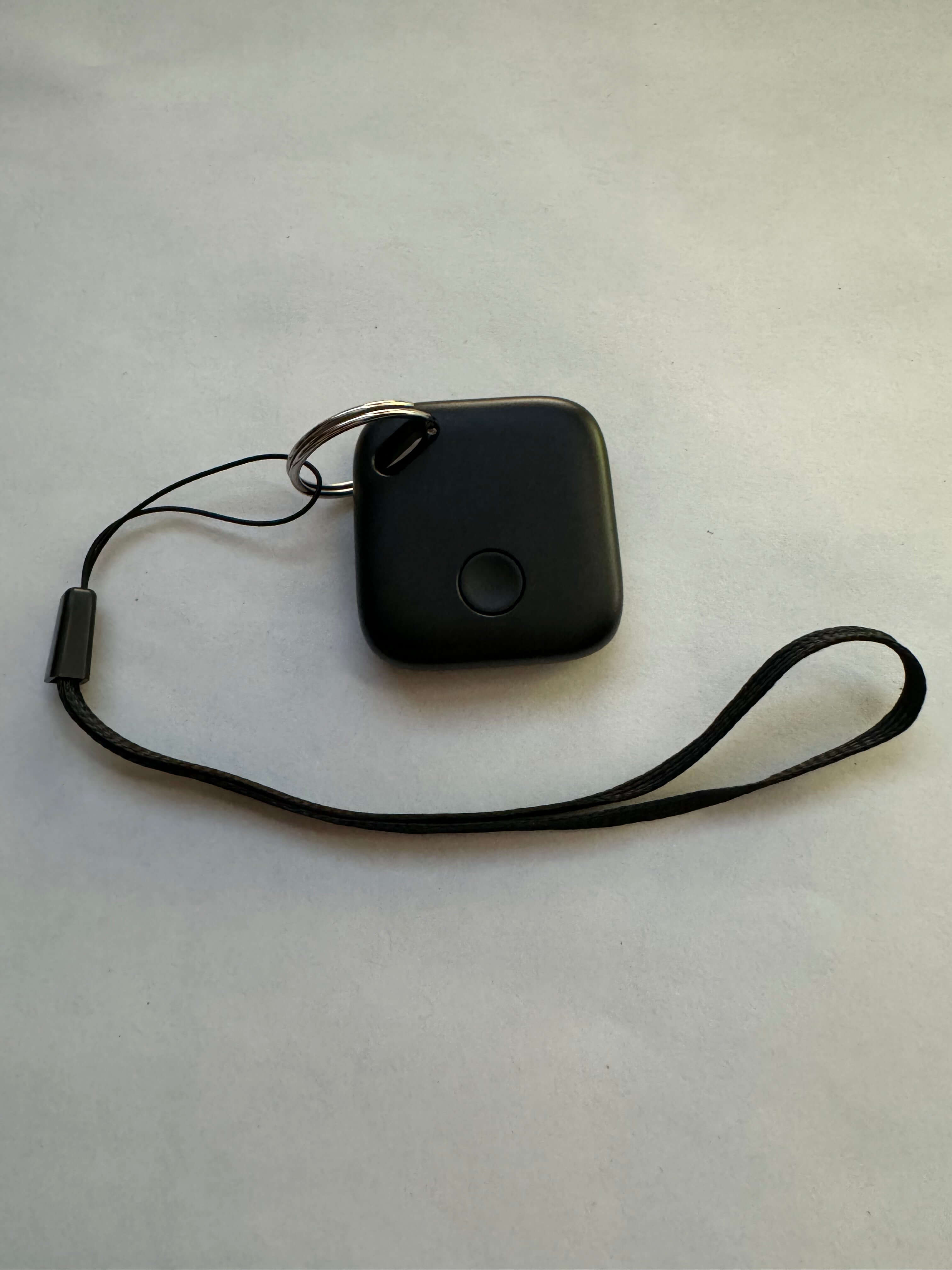 Black square key finder with lanyard on white background, kitchen gadget accessory