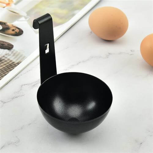 Black metal kitchen ladle with a hook handle on marble countertop, eggs nearby
