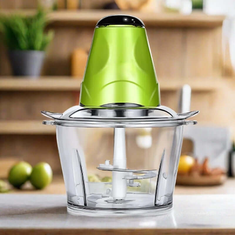 Electric food chopper with green lid and clear bowl on kitchen counter