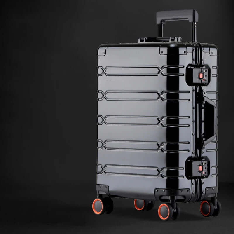 Sleek black hard shell rolling suitcase with orange-accented wheels on a dark background
