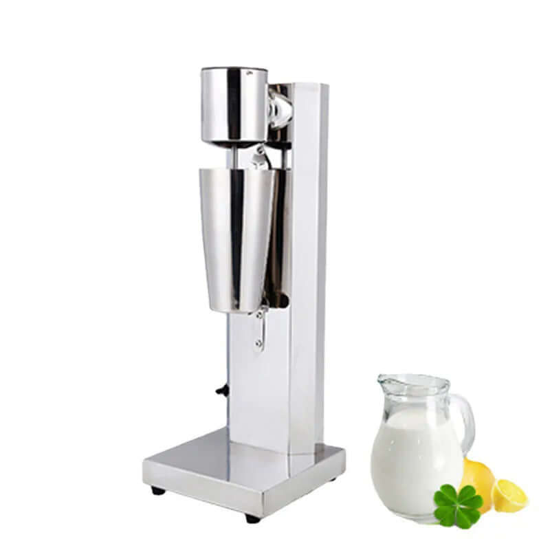 Stainless steel milkshake machine with a metal cup next to a jug of milk and lemons