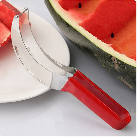Stainless steel watermelon slicer with red handle on plate, fresh watermelon in background