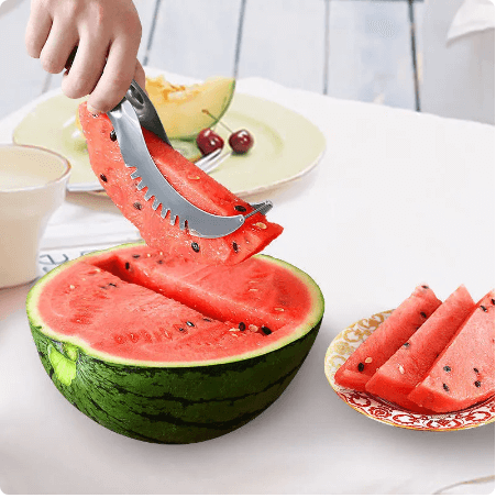 Watermelon slicer cutting fresh watermelon on kitchen table with fruit plate and utensils