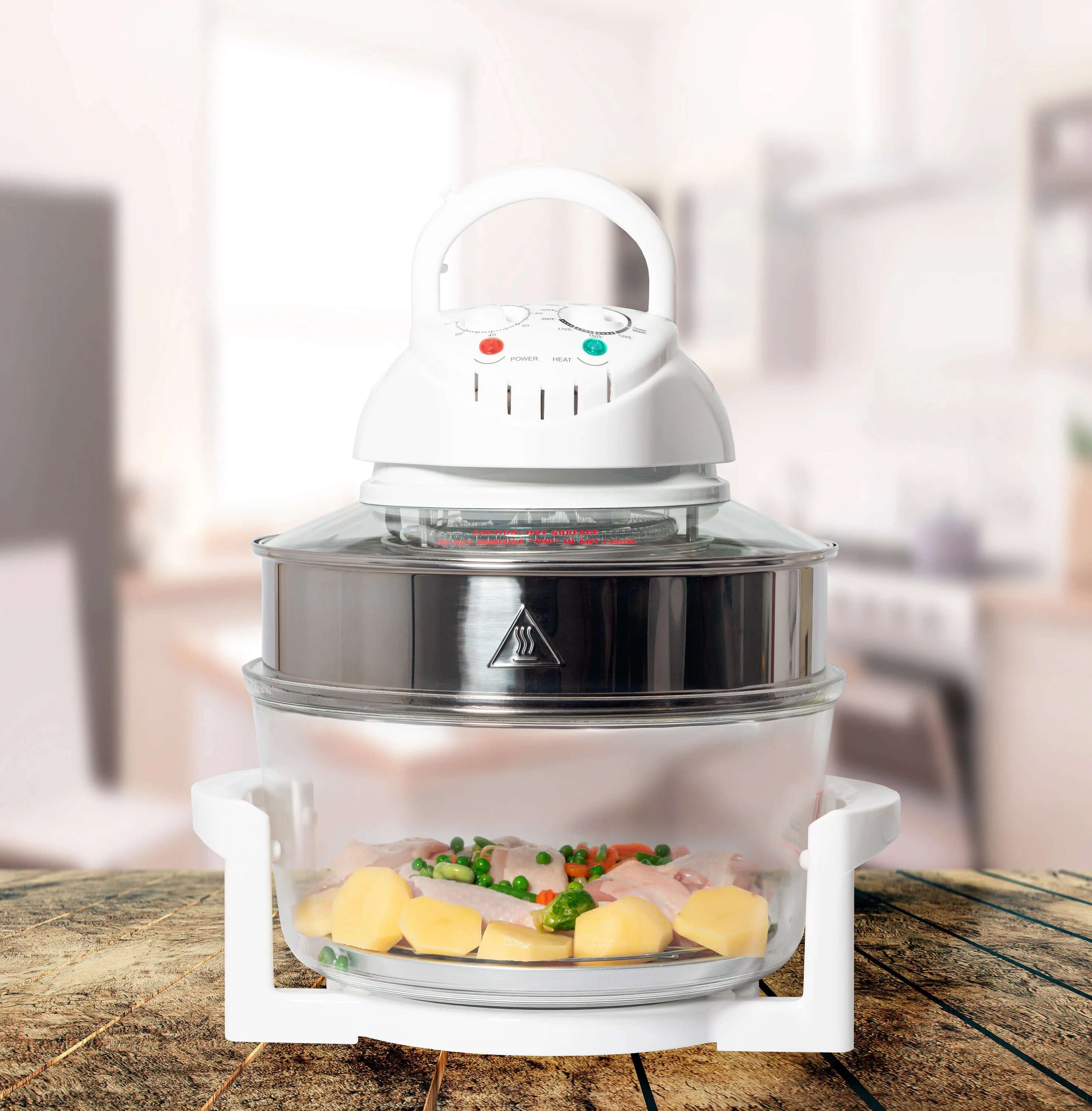 Halogen convection oven with timer, glass bowl, chicken, potatoes, and peas on a wooden counter