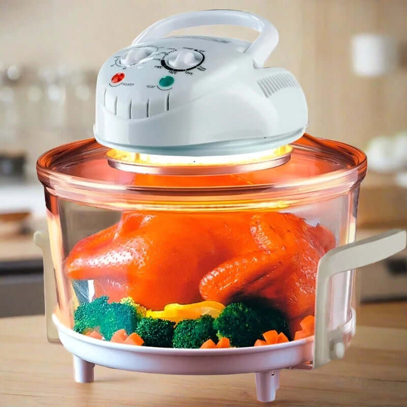 Halogen convection oven cooking whole chicken with vegetables in glass bowl on kitchen counter
