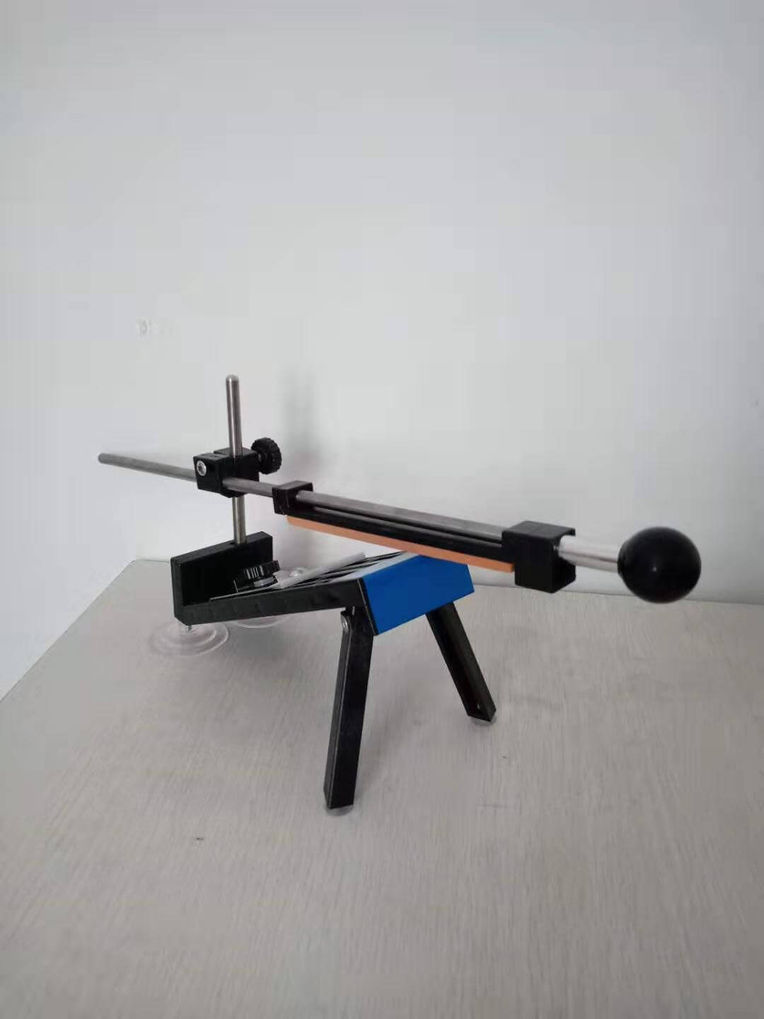 Adjustable knife sharpening tool with handle and guide on a tabletop surface