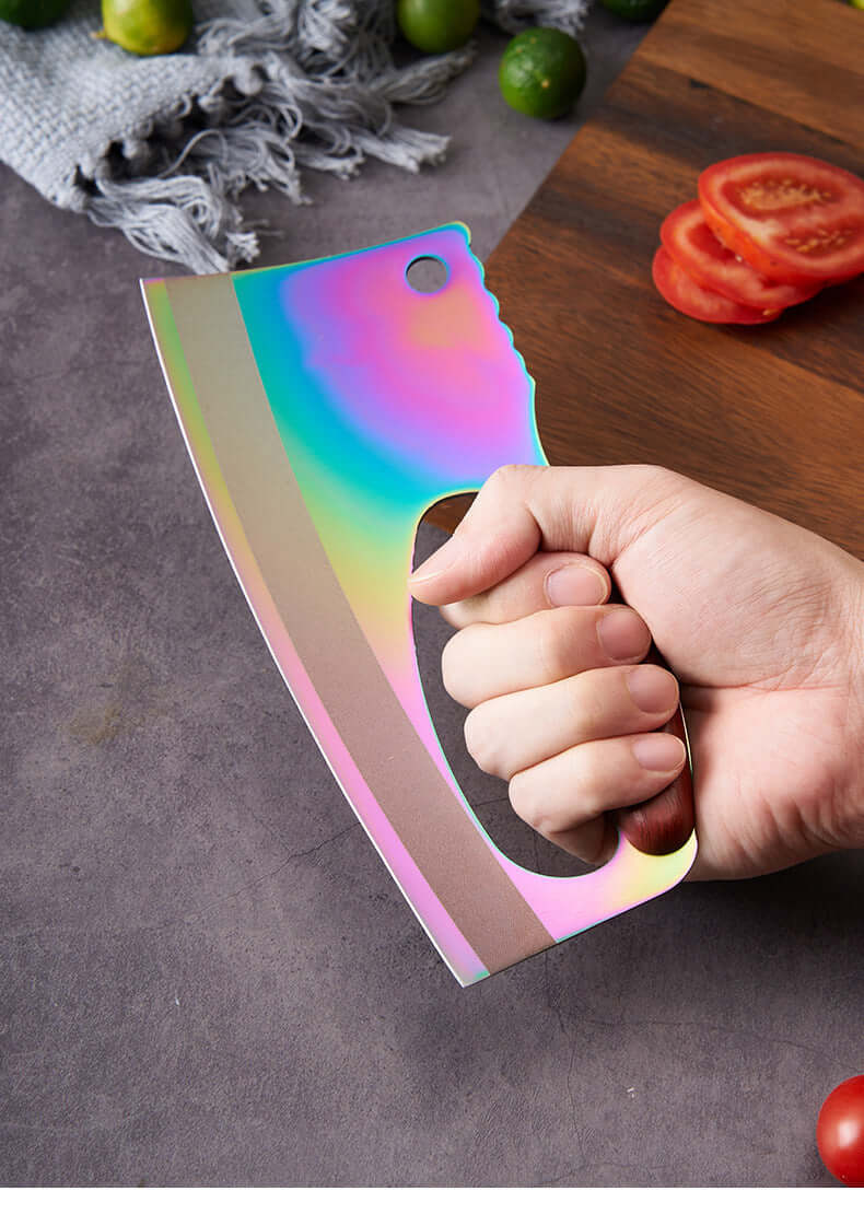 Hand holding rainbow cleaver knife on kitchen counter with tomatoes and limes