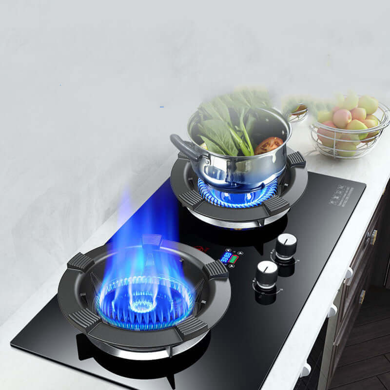 Modern glass gas stove with two burners, one cooking vegetables in a pot, kitchen countertop scene