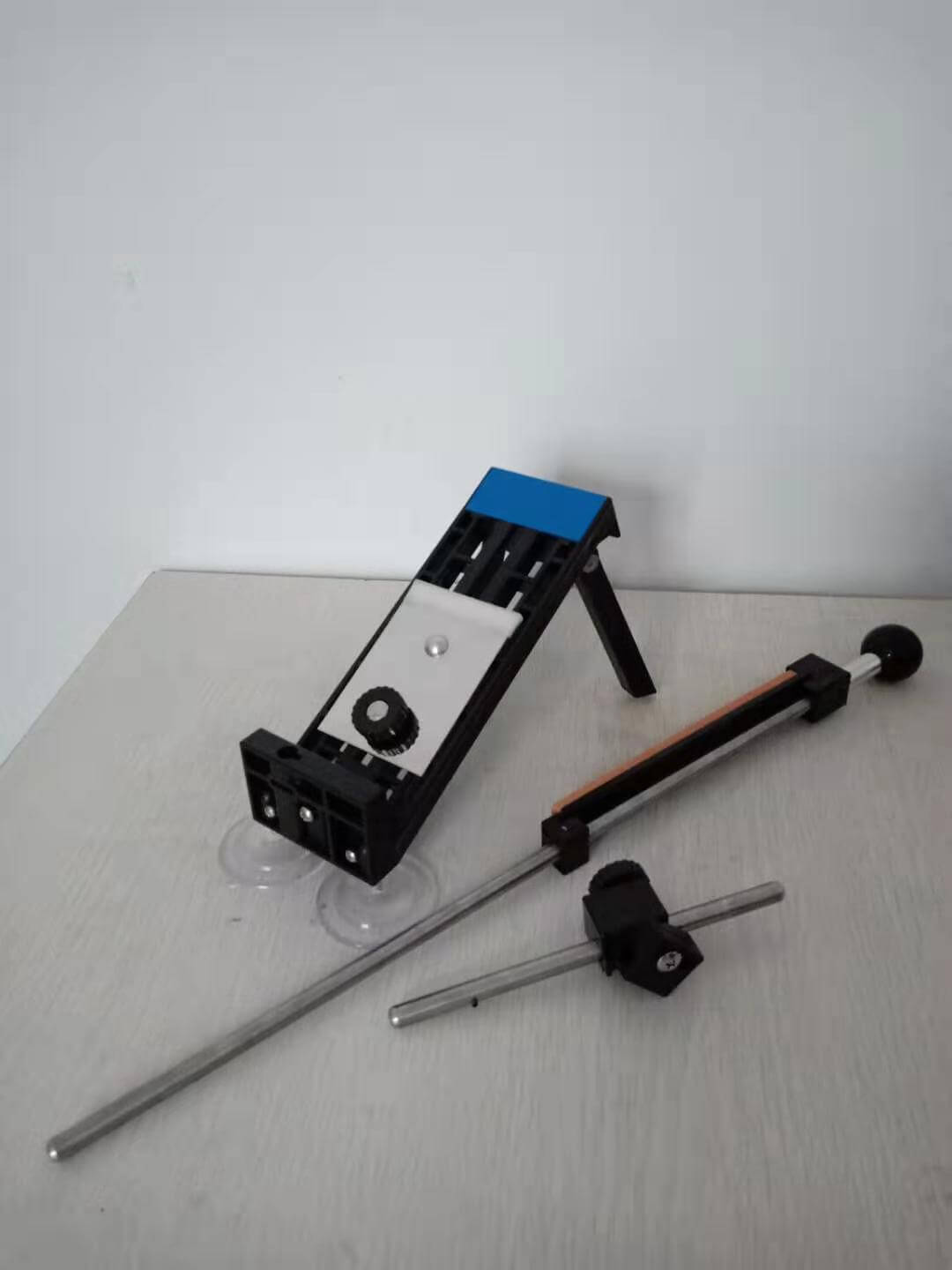 Adjustable kitchen knife sharpening system with base and guide rods on white surface