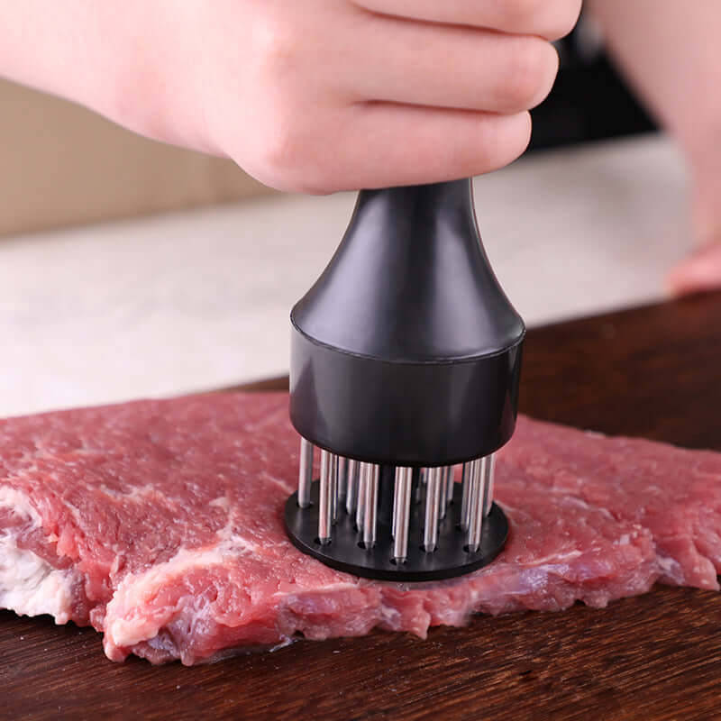 Hand using meat tenderizer tool on raw steak on wooden cutting board, kitchen accessory