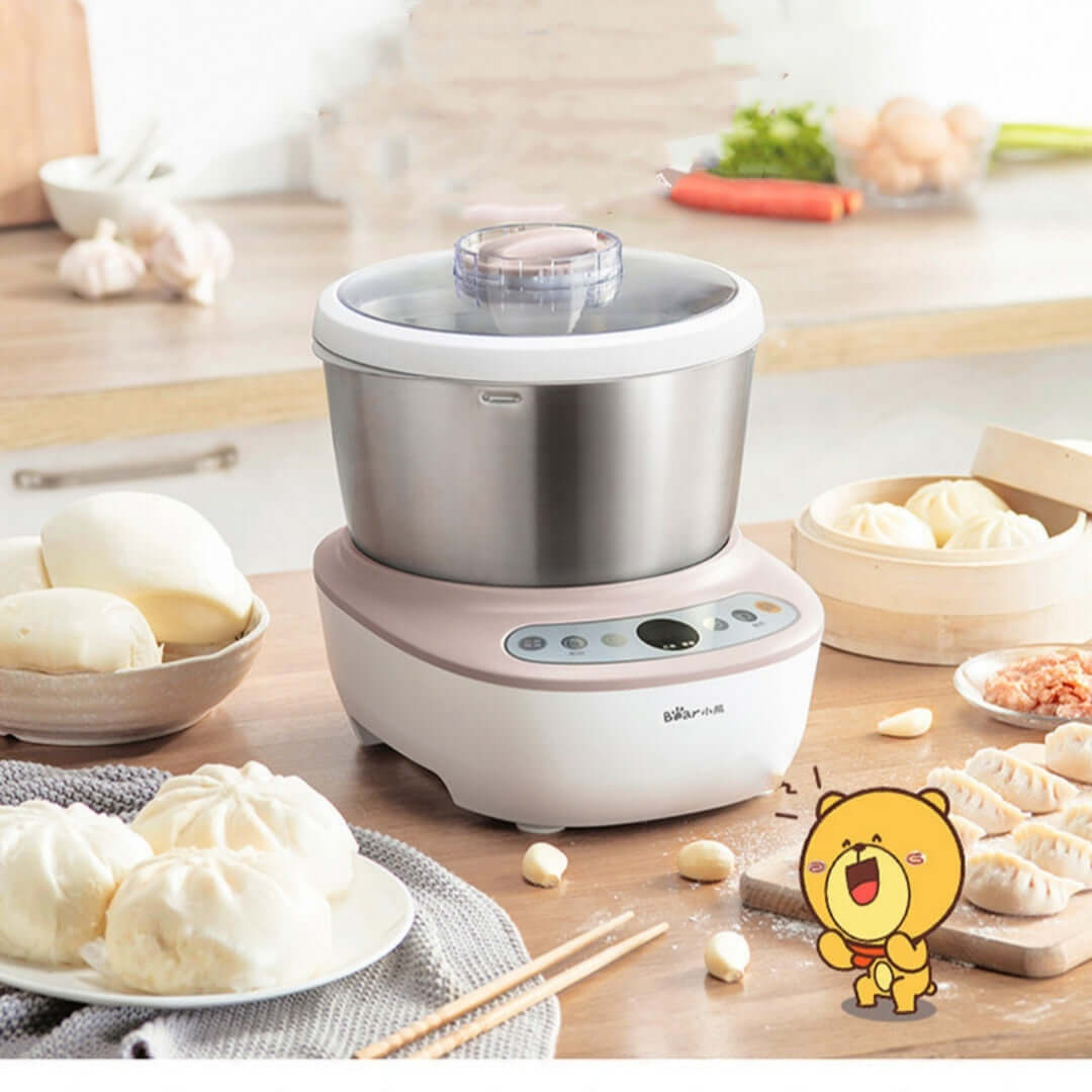Electric dough kneading machine on a kitchen counter with steamed buns and dumplings