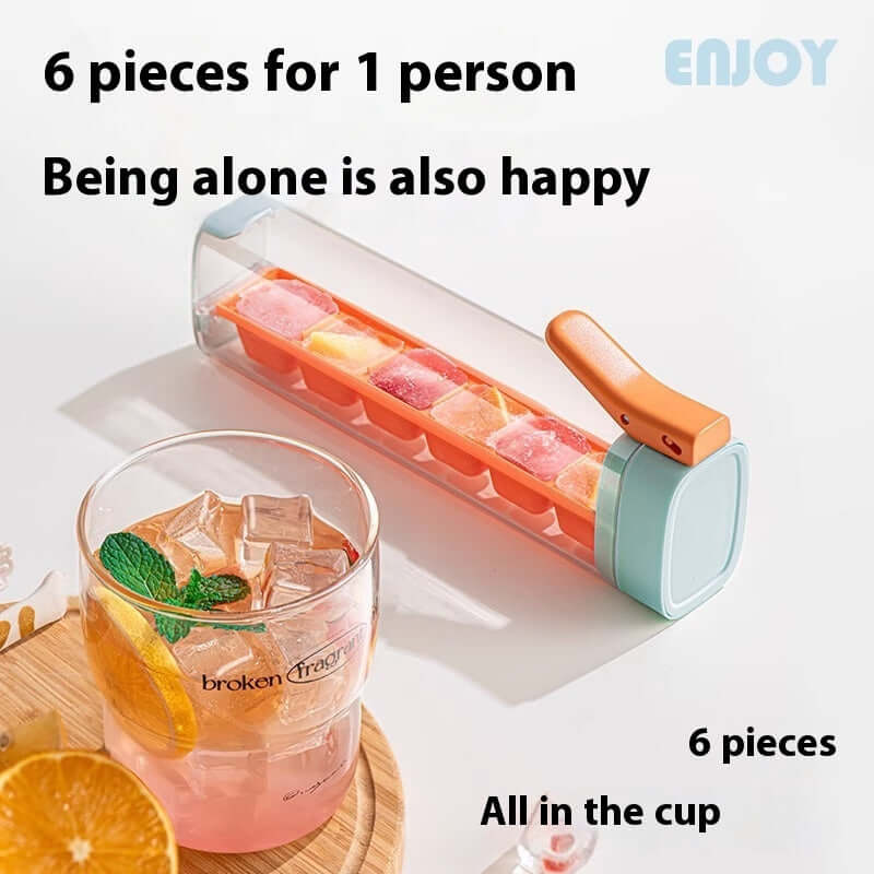Ice cube tray with colorful cubes and orange drink in glass, kitchen accessory product.