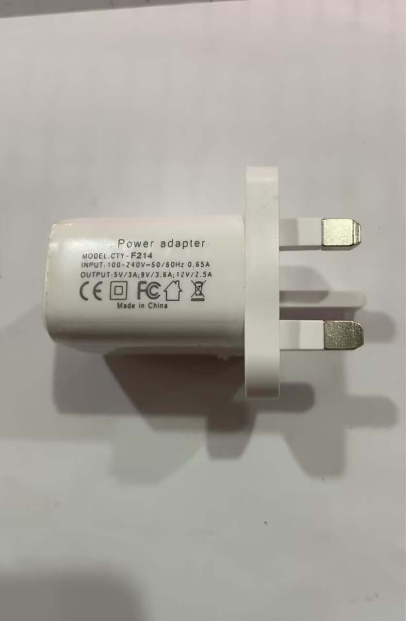 White power adapter with three-prong UK plug, technical specs and certification symbols visible