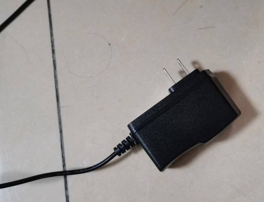 Black kitchen appliance power adapter with two prongs on a tiled floor