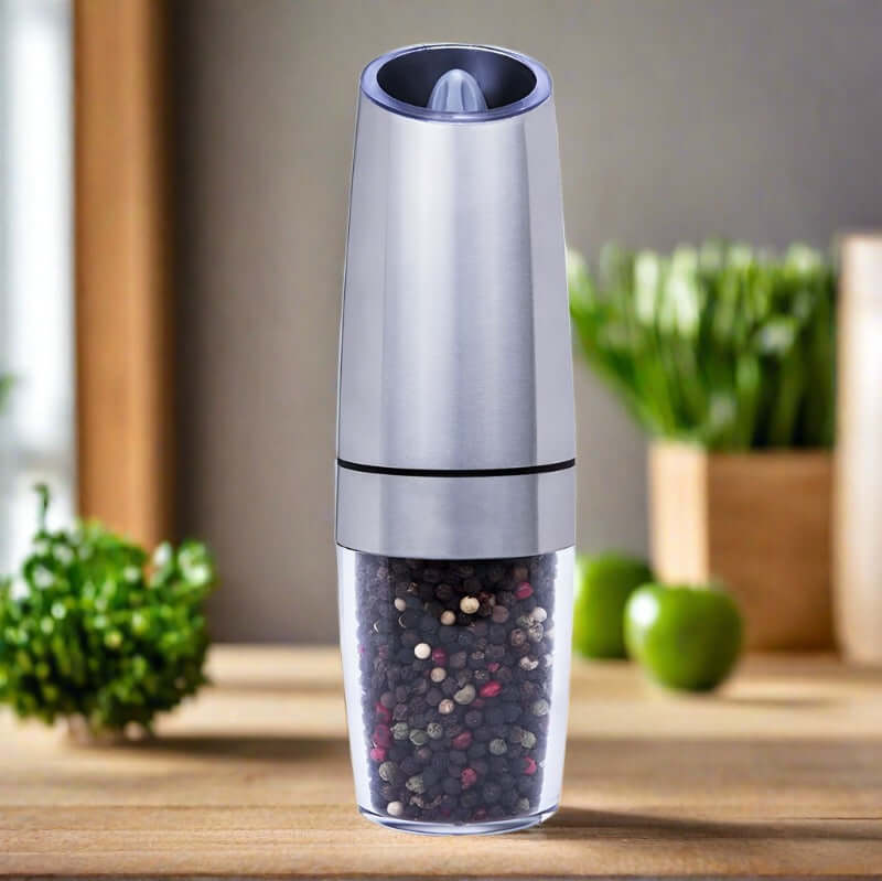 Stainless steel pepper grinder filled with peppercorns on kitchen countertop
