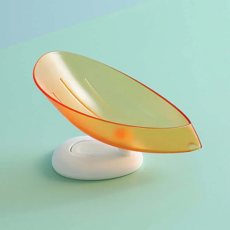 Leaf-shaped orange soap dish with drainage slots on a white base, kitchen accessory