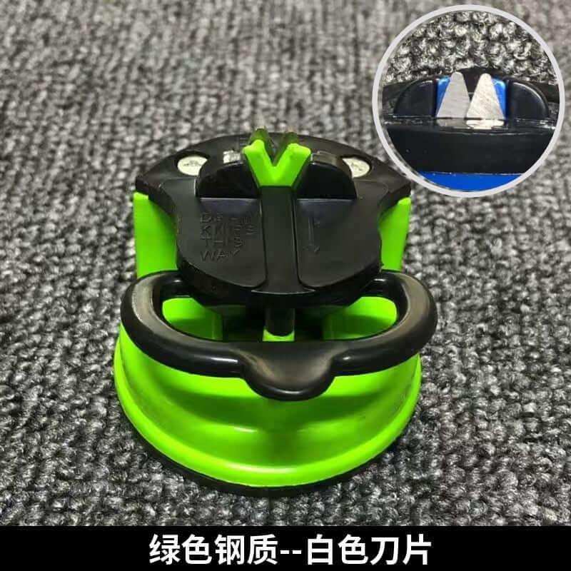 Green kitchen knife sharpener with black handle on textured surface, close-up of sharpening blades inset