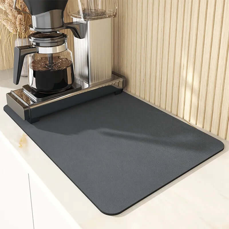 Coffee machine on kitchen counter with large black silicone mat