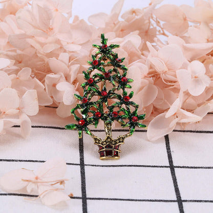Decorative Christmas tree brooch with green leaves and red accents, floral background