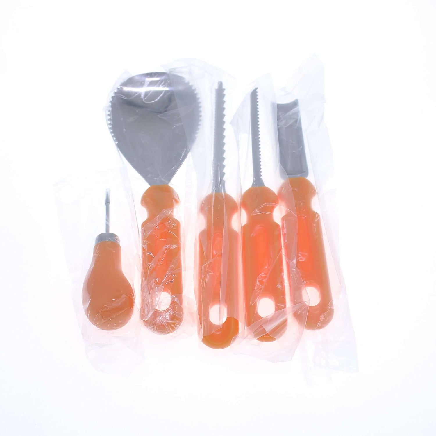 Set of orange-handled kitchen utensils in plastic packaging on white background