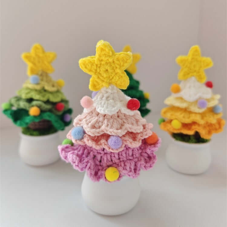 Colorful crocheted Christmas tree decorations with star toppers and pom-poms in white pots