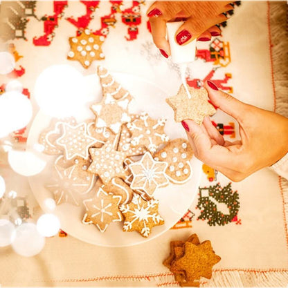 Decorating holiday star-shaped cookies with icing on a festive table setting