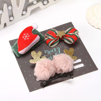 Set of festive hair clips with Santa hat, striped bow, gold antlers, and pink pom poms on display card