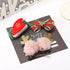 Set of festive hair clips with Santa hat, striped bow, gold antlers, and pink pom poms on display card