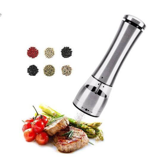 Stainless steel electric pepper grinder seasoning steak and vegetables, assorted peppercorns.