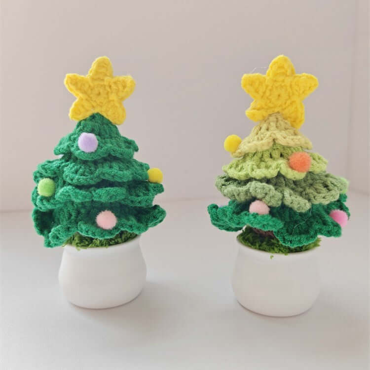 Two small crochet Christmas trees with yellow stars and colorful pom-poms in white pots
