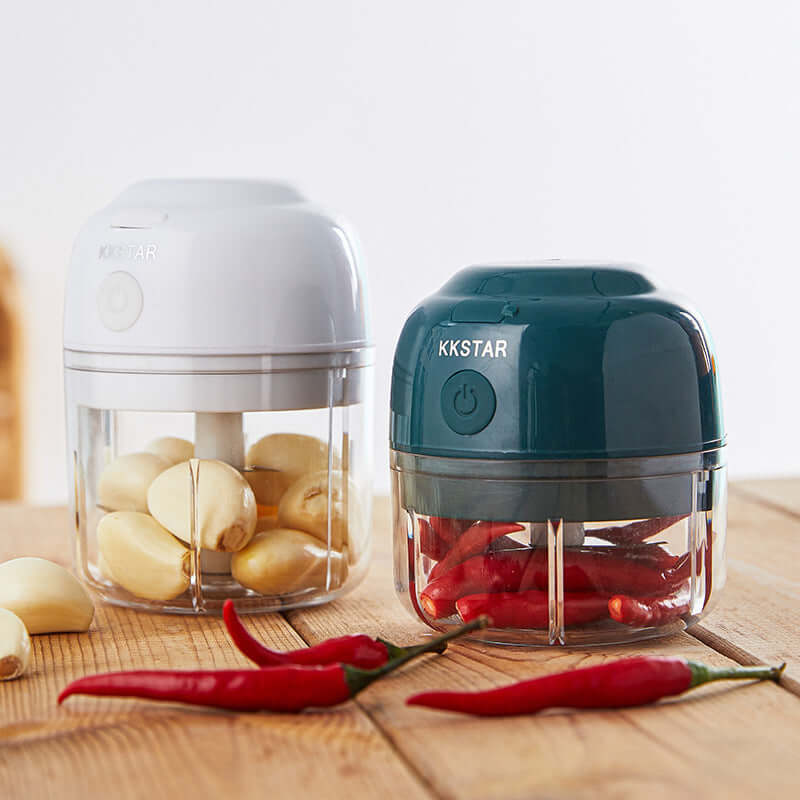Electric mini food choppers with garlic and chili peppers on a wooden kitchen table