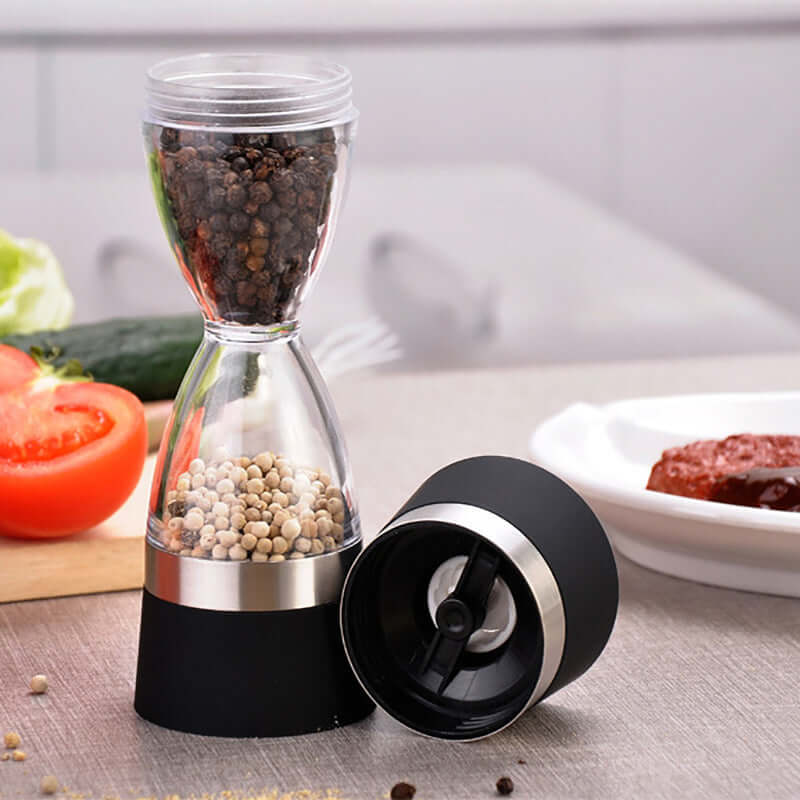 Dual chamber pepper grinder with black and white peppercorns on a kitchen counter