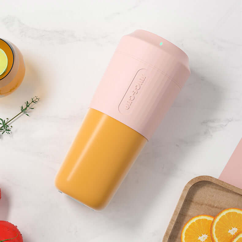 Portable pink and yellow blender bottle on marble countertop with orange slices
