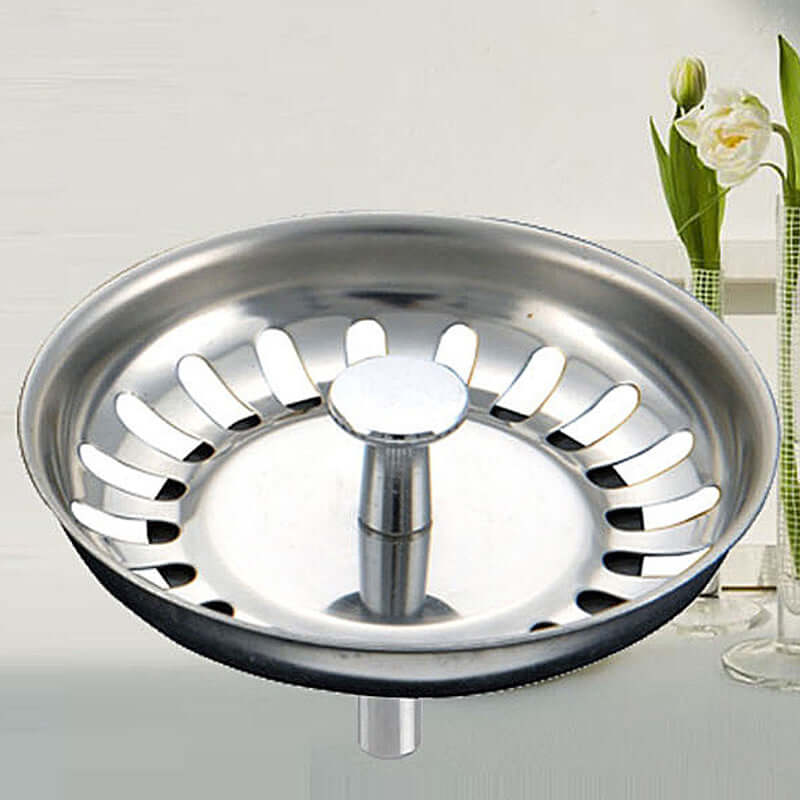 Stainless steel kitchen sink strainer basket with central handle in modern kitchen setting