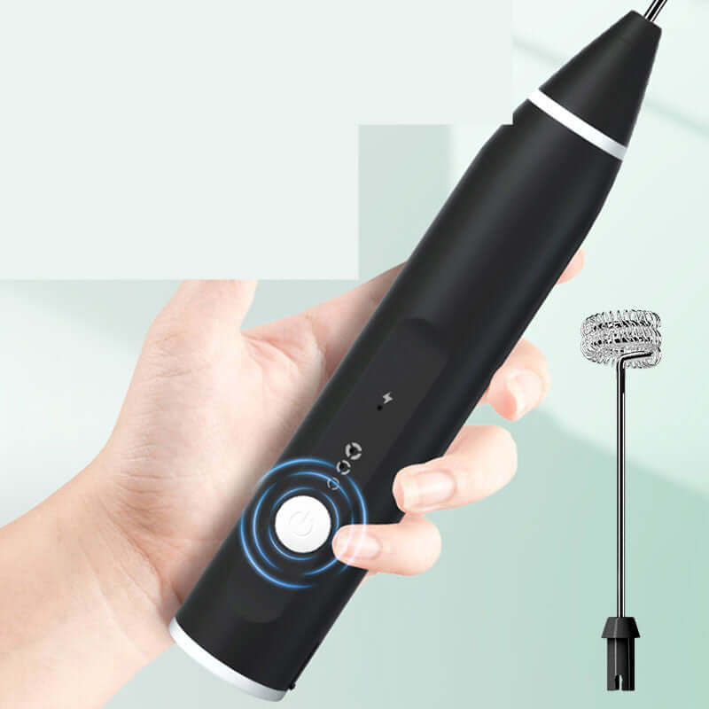 Hand holding electric milk frother with stainless steel whisk attachment