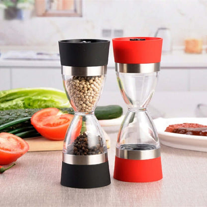 Dual manual spice grinders with black and red bases on kitchen countertop with vegetables