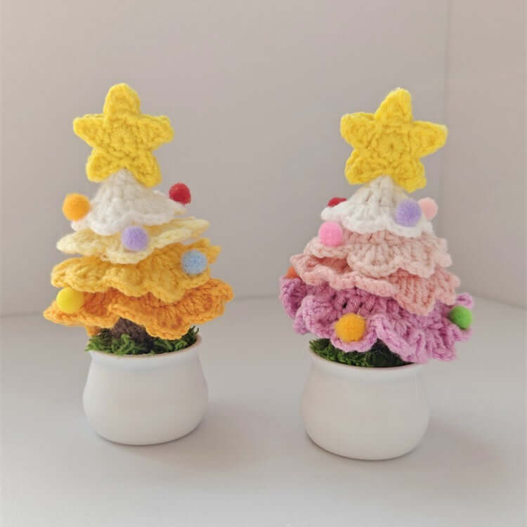 Two colorful crochet Christmas tree decorations in white pots, topped with yellow stars.