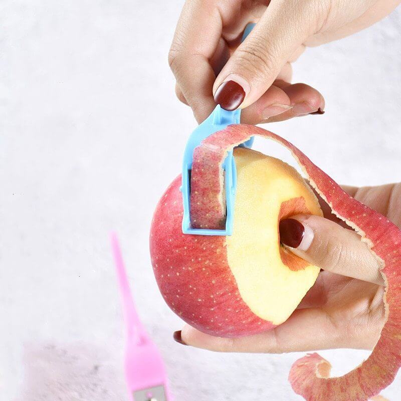 Hand using blue vegetable peeler to peel red apple, kitchen tool demonstration