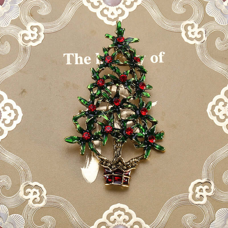 Festive Christmas tree brooch with green and red crystals on decorative background
