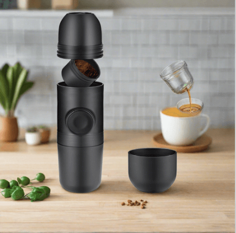 Portable manual espresso coffee maker with cup on kitchen counter, coffee being poured.