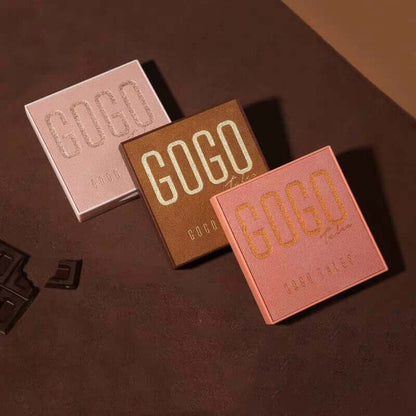 Three GOGO labeled square chocolate boxes in pink, brown, and peach on a brown surface