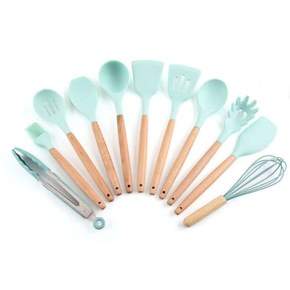 Set of mint green silicone kitchen utensils with wooden handles on white background