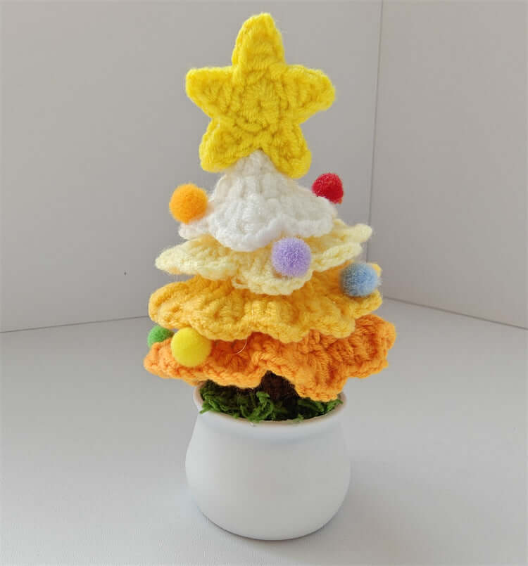 Crocheted Christmas tree decor with yellow star and pom poms in a small white pot